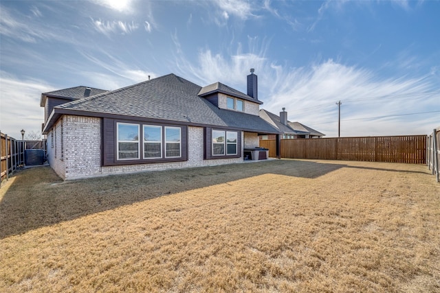 back of house with central AC unit and a yard