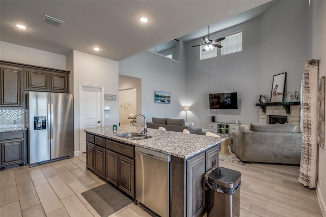 kitchen with sink, dark brown cabinetry, stainless steel appliances, and a kitchen island with sink