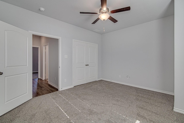 unfurnished bedroom with ceiling fan and dark colored carpet