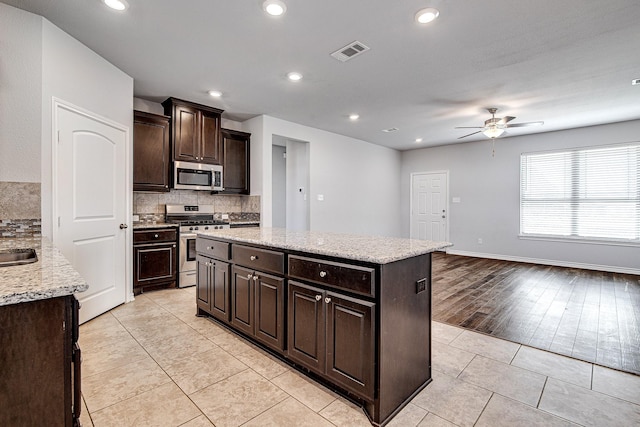 kitchen with stainless steel appliances, ceiling fan, light tile patterned floors, decorative backsplash, and dark brown cabinets