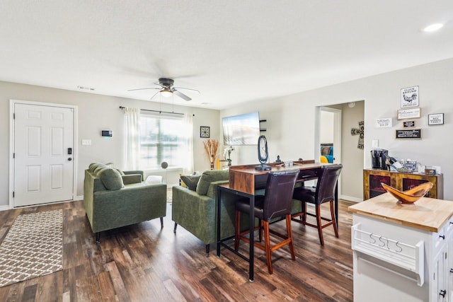 living room featuring ceiling fan and dark hardwood / wood-style floors