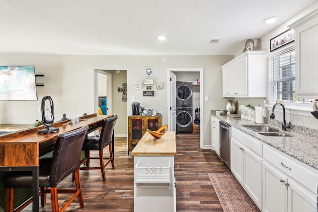 kitchen featuring sink, wooden counters, white cabinetry, and stacked washer and dryer