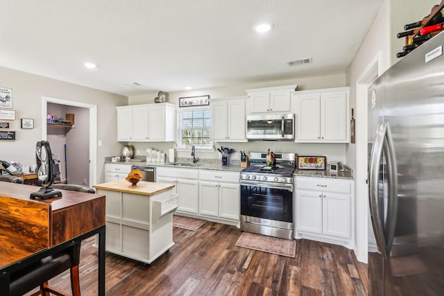 kitchen featuring stainless steel appliances, sink, white cabinets, light stone countertops, and dark hardwood / wood-style flooring