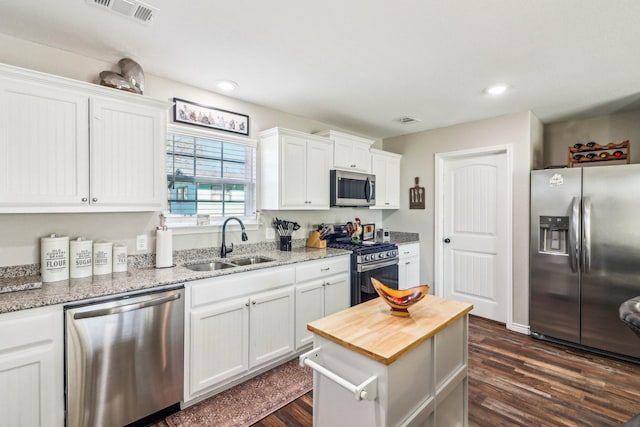 kitchen with light stone counters, stainless steel appliances, dark hardwood / wood-style flooring, white cabinets, and sink