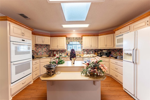 kitchen with white appliances, a center island, a skylight, and crown molding