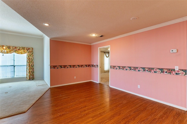 unfurnished room with a textured ceiling, ornamental molding, and wood-type flooring