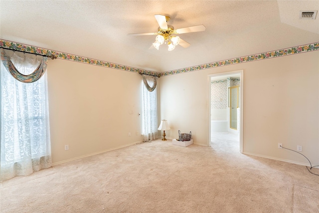 spare room with ceiling fan, light colored carpet, and a textured ceiling