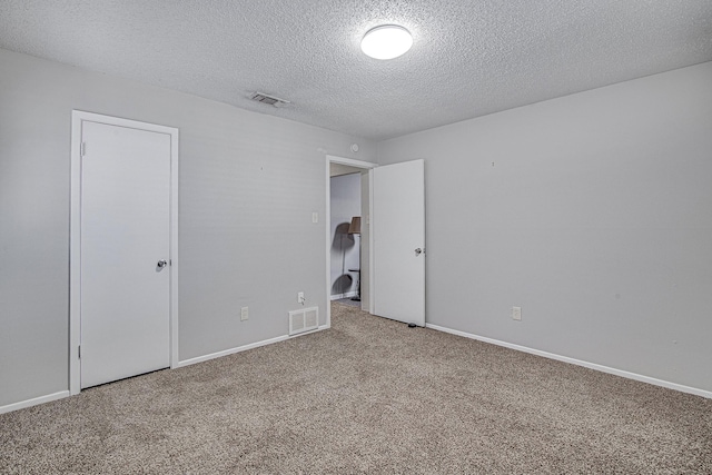 spare room with a textured ceiling and carpet flooring