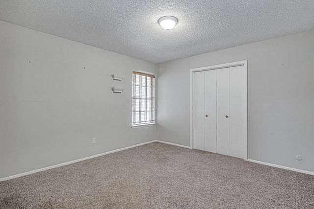 unfurnished bedroom featuring a textured ceiling, carpet floors, and a closet