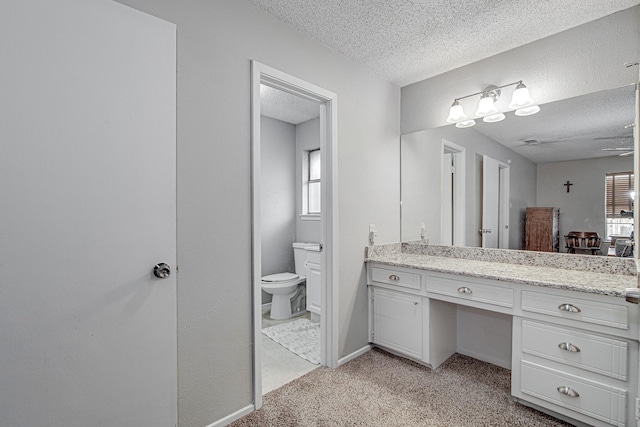 bathroom featuring a textured ceiling, plenty of natural light, vanity, and toilet