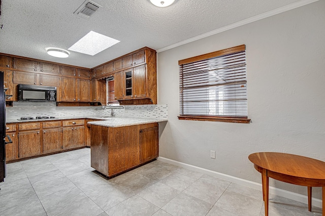 kitchen featuring kitchen peninsula, black appliances, a skylight, crown molding, and sink