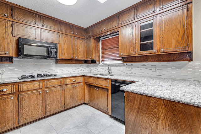 kitchen with light stone counters, a textured ceiling, black appliances, light tile patterned flooring, and sink