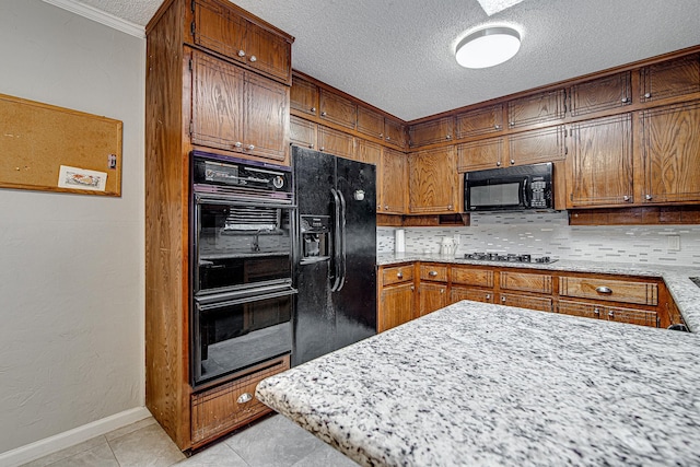 kitchen with a textured ceiling, light tile patterned floors, black appliances, decorative backsplash, and ornamental molding