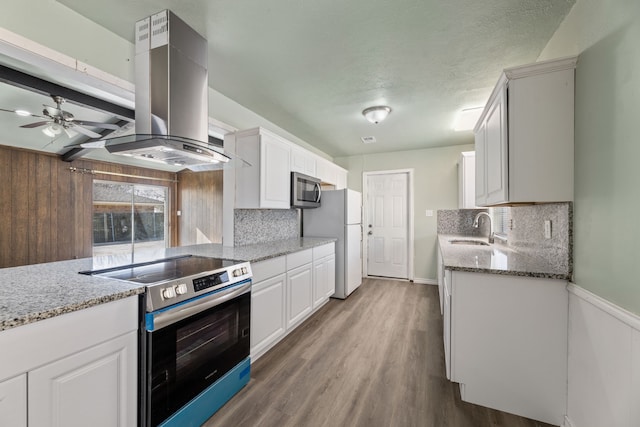 kitchen with stainless steel appliances, sink, white cabinetry, light stone countertops, and island range hood