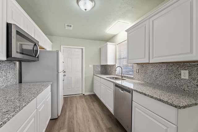 kitchen featuring stainless steel appliances, white cabinets, sink, and light stone counters