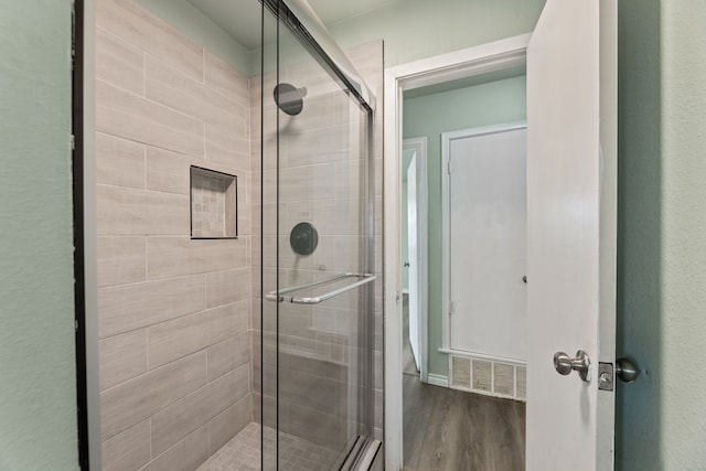 bathroom featuring a shower with shower door and hardwood / wood-style floors