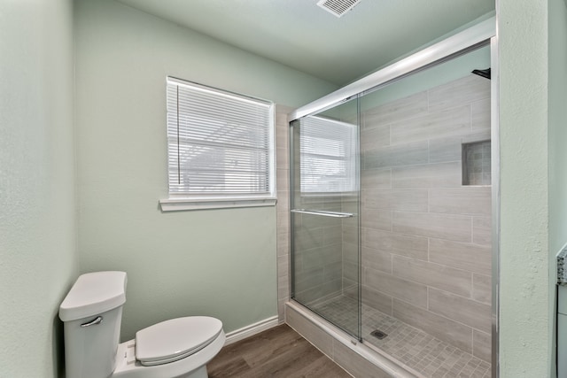 bathroom featuring toilet, an enclosed shower, and hardwood / wood-style floors