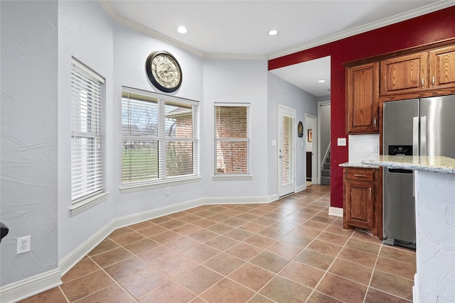 kitchen featuring stainless steel fridge, baseboards, light stone counters, and crown molding