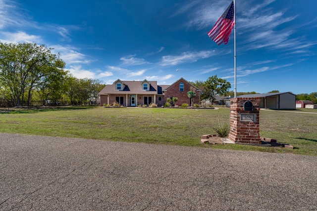 cape cod house featuring brick siding and a front yard