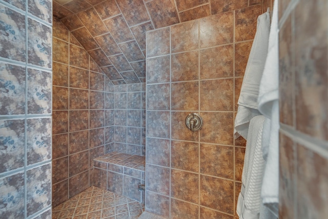 bathroom featuring a tile shower and lofted ceiling