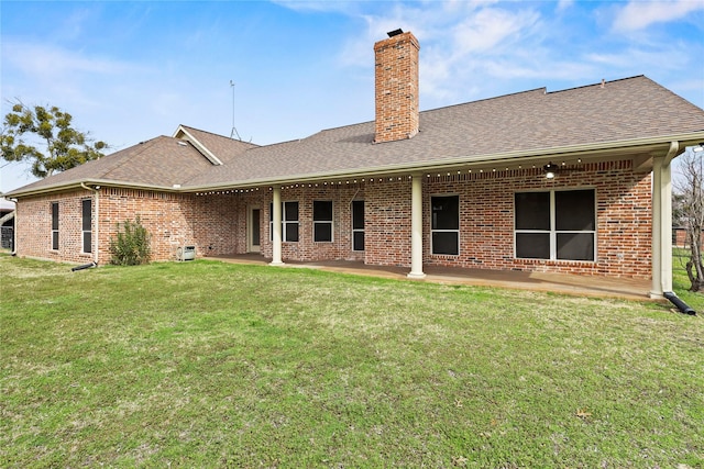 back of house featuring brick siding, a shingled roof, and a patio