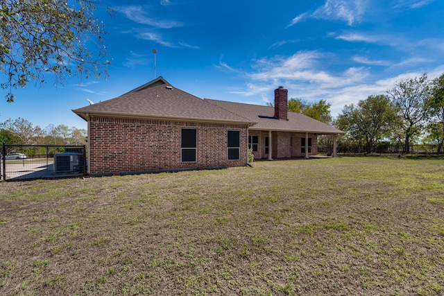 back of house with central air condition unit and a yard