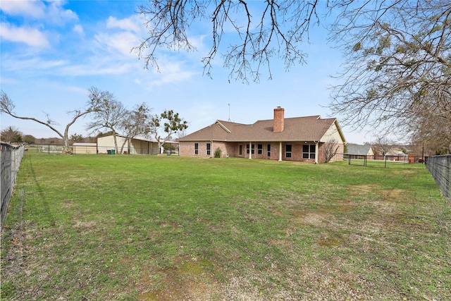 back of house featuring brick siding, a lawn, a chimney, and a fenced backyard