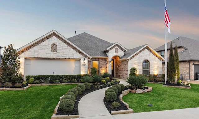 french country home featuring a garage and a lawn