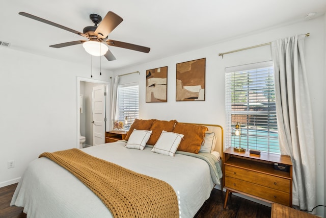 bedroom with ensuite bath, ceiling fan, and dark hardwood / wood-style floors