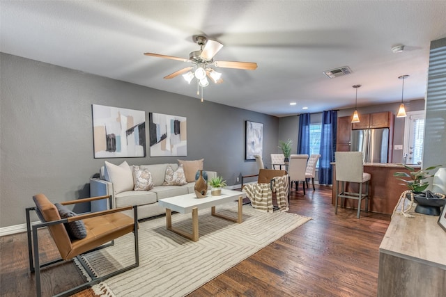 living room featuring dark wood-type flooring and ceiling fan