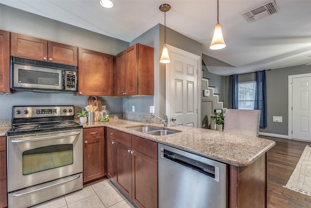 kitchen with appliances with stainless steel finishes, pendant lighting, kitchen peninsula, and sink