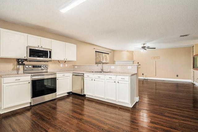 kitchen with sink, kitchen peninsula, white cabinets, and appliances with stainless steel finishes