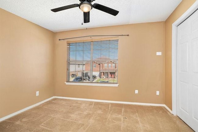 spare room featuring light carpet, ceiling fan, and a textured ceiling