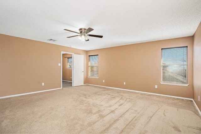 empty room featuring light colored carpet, a textured ceiling, and ceiling fan