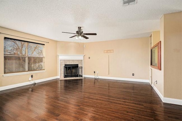 unfurnished living room featuring dark hardwood / wood-style flooring, a textured ceiling, ceiling fan, and a fireplace