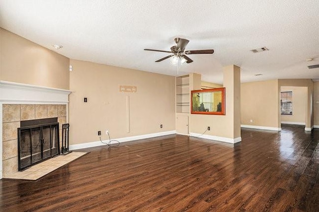 unfurnished living room featuring dark wood-type flooring, ceiling fan, a fireplace, and a textured ceiling