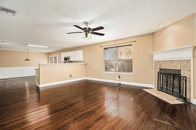 unfurnished living room with hardwood / wood-style flooring, ceiling fan, a textured ceiling, and a fireplace