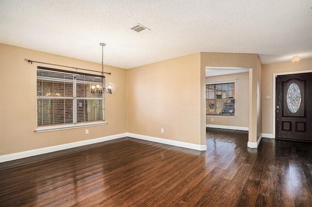 foyer with dark wood-type flooring, a chandelier, and a textured ceiling