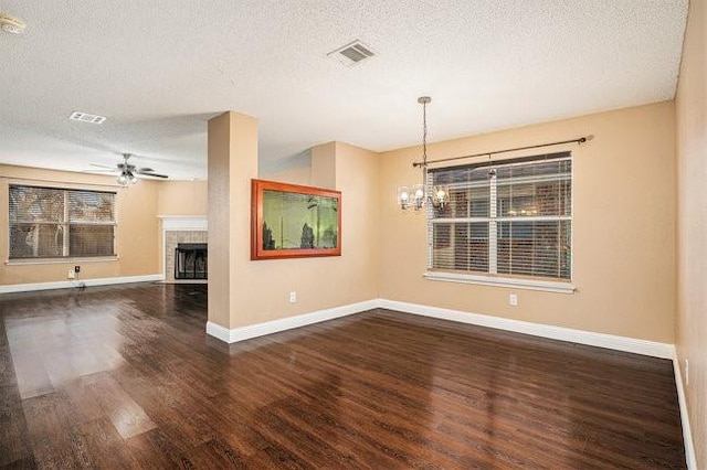 unfurnished room featuring dark wood-type flooring, ceiling fan with notable chandelier, a textured ceiling, and a fireplace