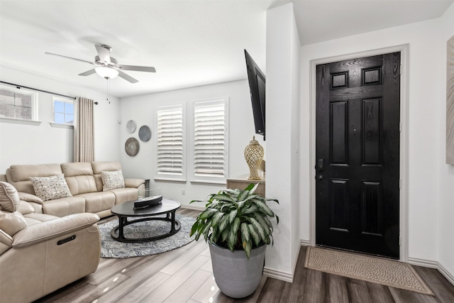 living area featuring baseboards, ceiling fan, and wood finished floors