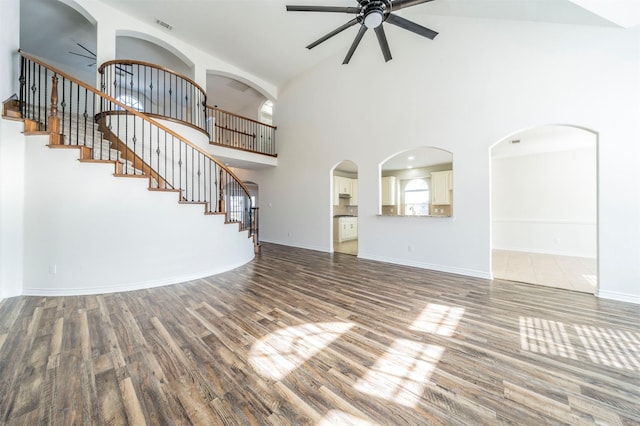 unfurnished living room with a high ceiling, ceiling fan, and wood-type flooring