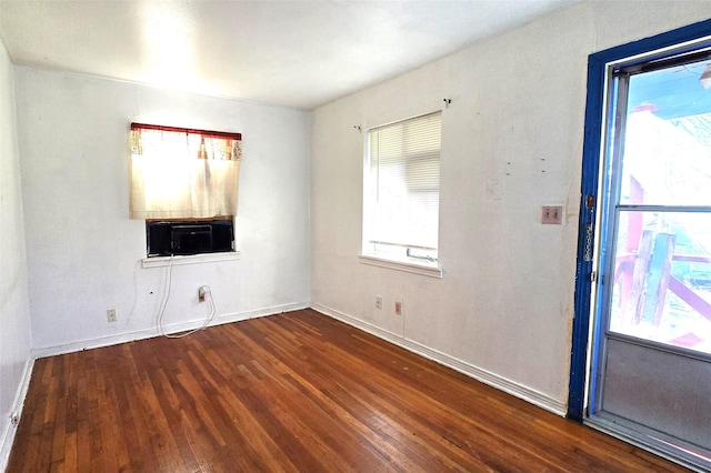 empty room with dark hardwood / wood-style flooring and plenty of natural light