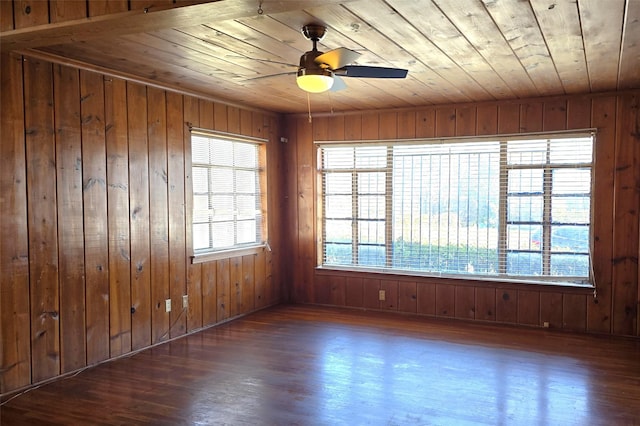 empty room with ceiling fan, dark hardwood / wood-style flooring, wooden ceiling, and a wealth of natural light