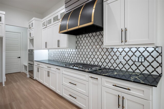 kitchen featuring sink, white cabinetry, a kitchen island with sink, stainless steel appliances, and exhaust hood