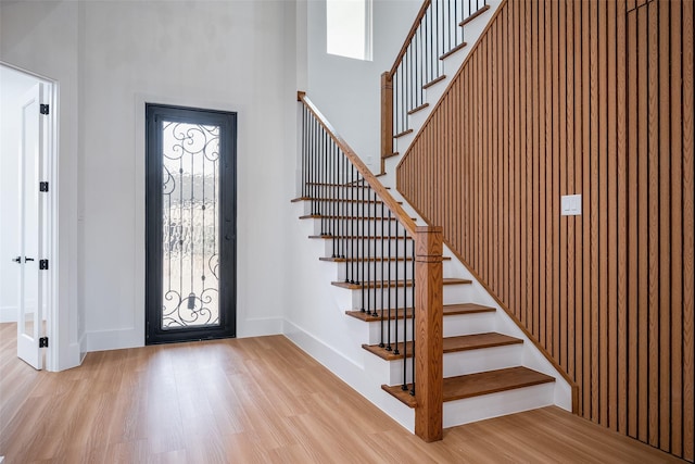 foyer featuring stairway, wood finished floors, baseboards, and a towering ceiling