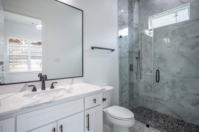 bathroom featuring a marble finish shower, toilet, and vanity