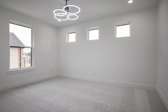 carpeted empty room with baseboards, recessed lighting, and a chandelier