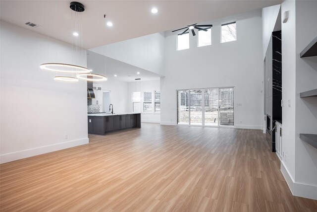 unfurnished living room with a fireplace, light hardwood / wood-style floors, built in features, and a high ceiling