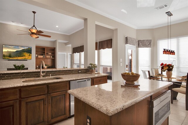 kitchen featuring sink, stainless steel appliances, light stone counters, a kitchen island, and kitchen peninsula