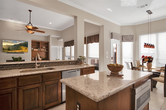 kitchen with light stone counters, stainless steel appliances, a sink, visible vents, and crown molding